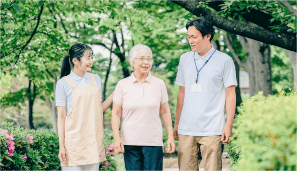 スタッフが患者に寄り添い、屋外で笑顔で歩く様子
